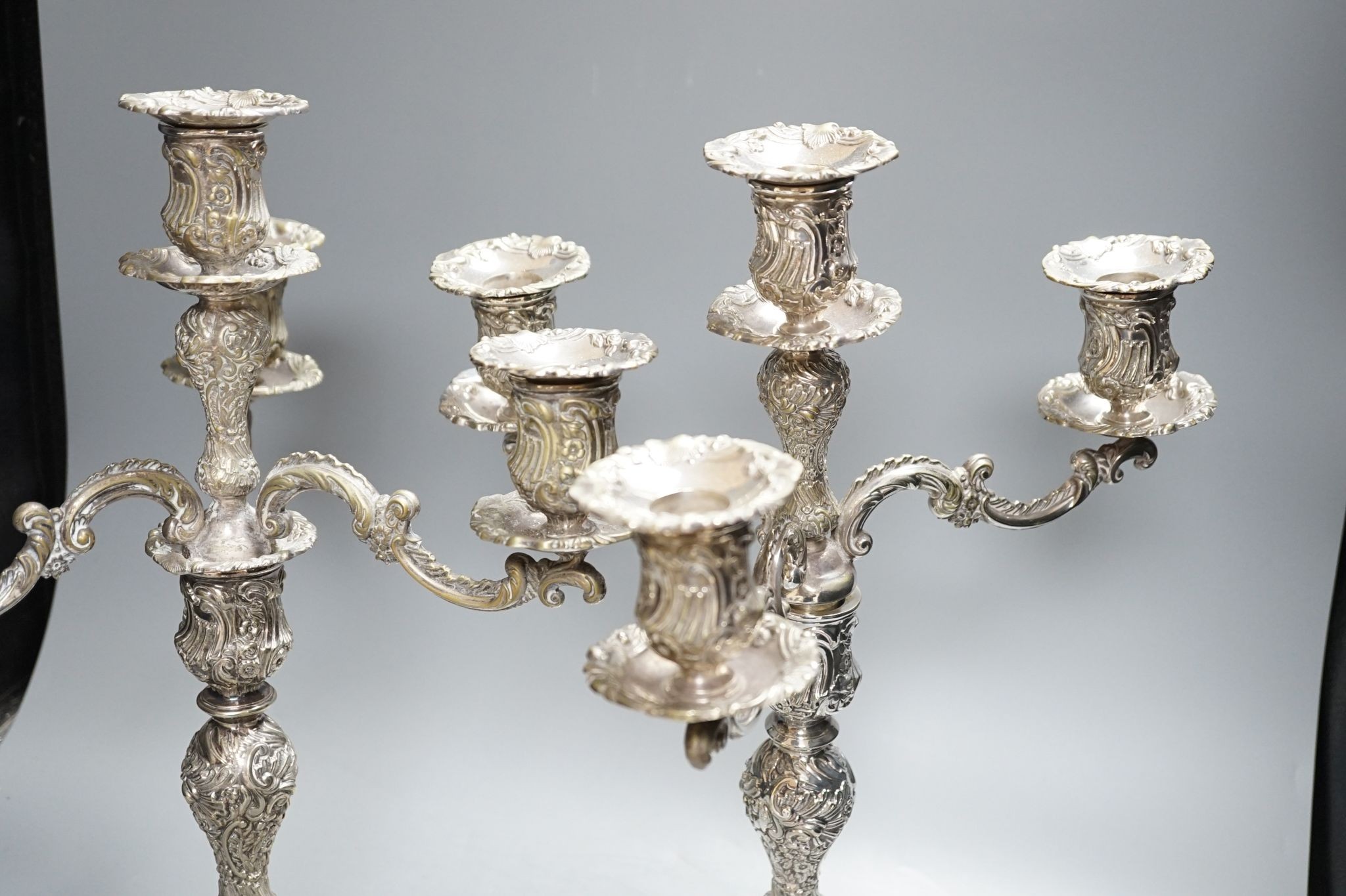 A pair of plated embossed three branch candelabra, 43cm